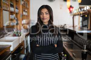 Beautiful waitress standing with arms crossed in bar