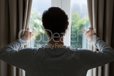 Woman looking through window at home