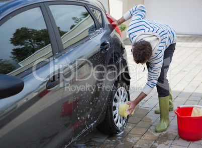 Auto service staff washing a car tyre with sponge