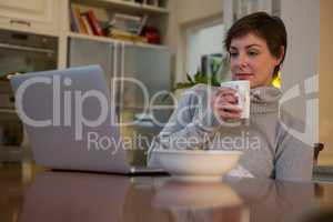 Woman having coffee while using laptop