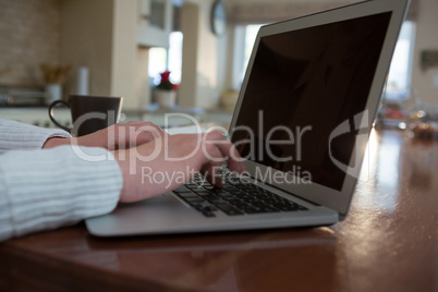 Woman using laptop in kitchen