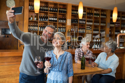 Senior couple taking selfie with mobile phone in restaurant
