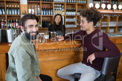 Waitress standing at counter while two men using mobile phone