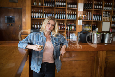 Beautiful woman holding glass of wine and mobile phone at counter Beautiful woman holding glass of wine and mobile phone at counter