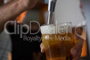 Brewer filling beer in beer glass from beer pump in bar