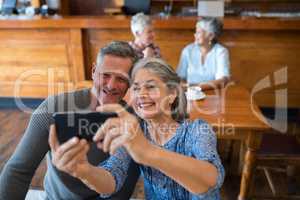 Senior couple taking selfie with mobile phone in restaurant
