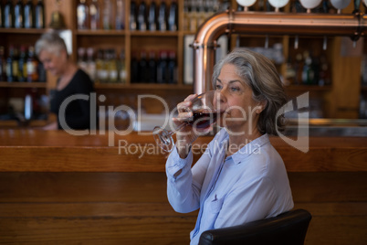 Senior woman having glass of red wine at counter