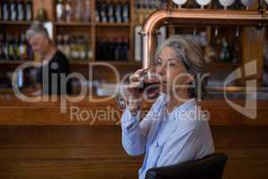 Senior woman having glass of red wine at counter