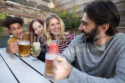 Friends interacting while having glass of drinks