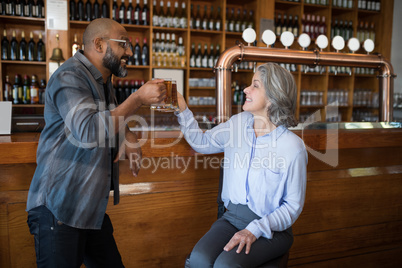 Two friends toasting glass of beer at counter in restaurant