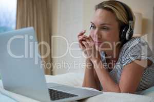 Woman using laptop while listening music on headphones