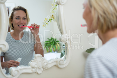 Reflection of woman brushing her teeth