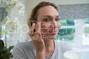 Woman applying moisturizer in bathroom
