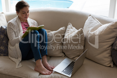 Woman reading book on sofa