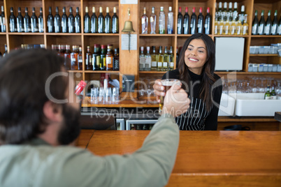 Waitress serving glass of beer to customer at counter