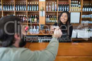 Waitress serving glass of beer to customer at counter