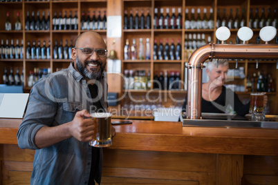 Smiling man having glass of beer in restaurant