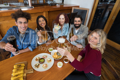 Happy friends showing glass of drinks in bar