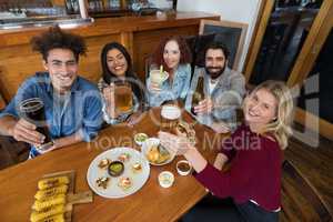 Happy friends showing glass of drinks in bar