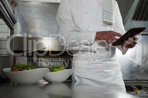 Male chef using mobile phone in the kitchen