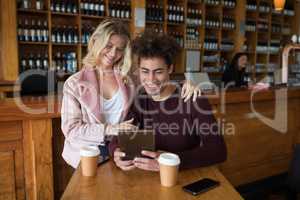 Couple using digital tablet in bar