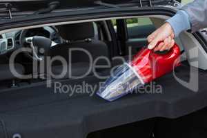 Auto service staff cleaning car with portable vacuum