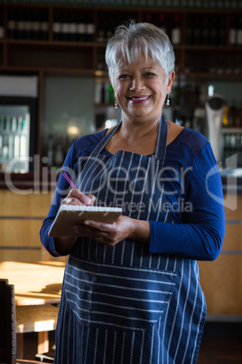 Waitress writing an order in the notepad in the bar