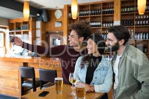 Friends taking selfie with mobile phone while having glass of beer