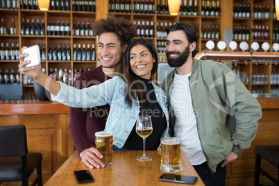 Friends taking selfie with mobile phone while having glass of beer Friends taking selfie with mobile phone while having glass of beer