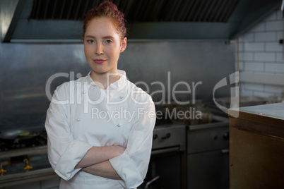 Smiling female chef with hands crossed in the kitchen Smiling female chef with hands crossed in the kitchen