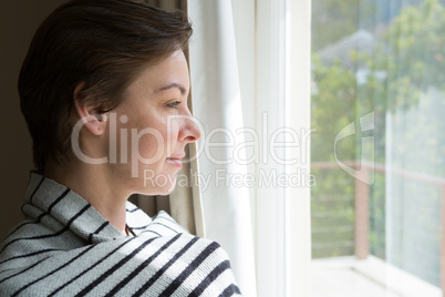 Woman looking through a window at home