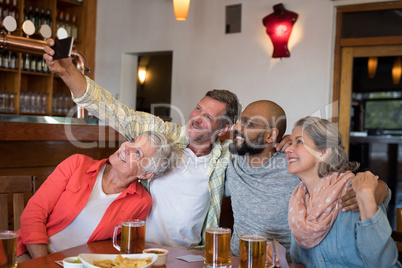 Friends taking selfie with mobile phone in bar