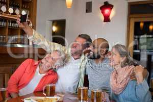 Friends taking selfie with mobile phone in bar