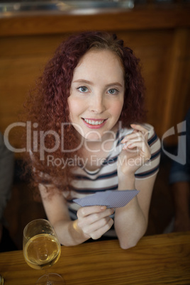 Beautiful woman holding cards in bar