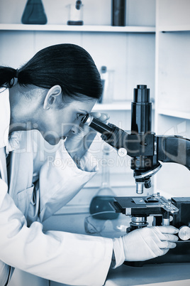 Darkhaired female looking through a microscope