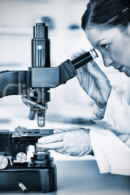 Beautiful redhaired scientist looking through a microscope