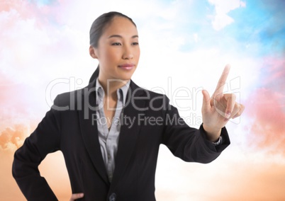 Businesswoman touching air in front of colorful clouds