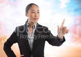 Businesswoman touching air in front of colorful clouds