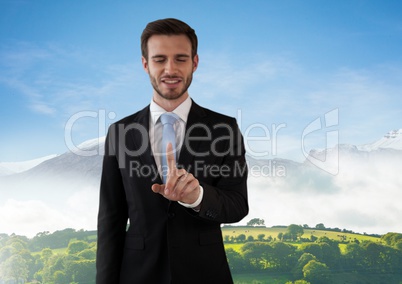 Businessman touching air in front of green hills