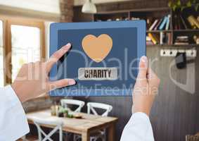 Hand holding tablet with charity text and heart icon