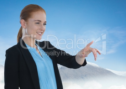 Businesswoman touching air in front of snow mountains and sky