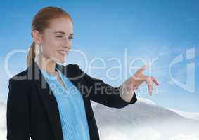 Businesswoman touching air in front of snow mountains and sky