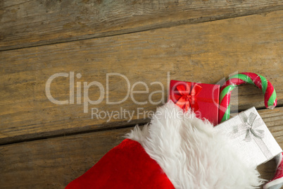 Wrapped gift box and candy cane in stocking against wooden wall