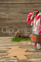 Pine cones and candy cane in jar against wooden plank