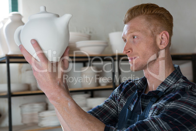 Male potter examining a teapot