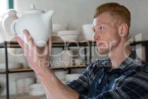 Male potter examining a teapot