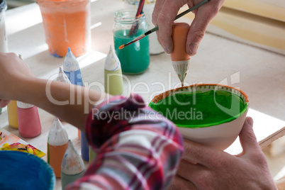 Male potter and girl painting bowl