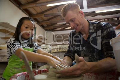 Male potter assisting his daughter in making a pot