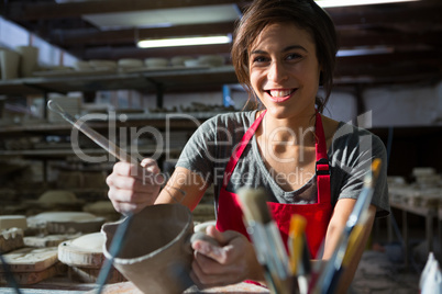 Portrait of female potter carving mug