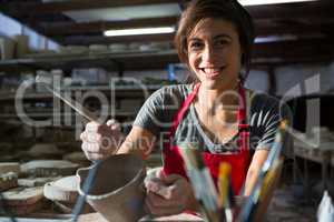 Portrait of female potter carving mug